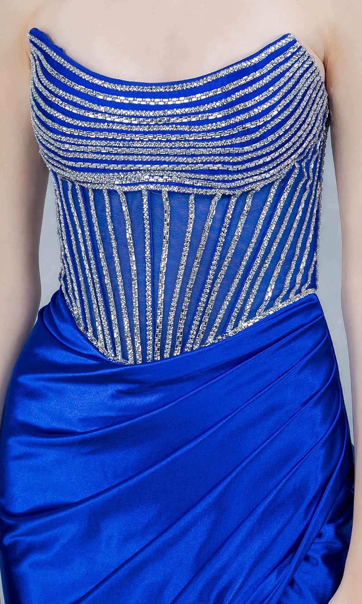 A woman wears the Cinderella Couture 8473J long prom dress, a strapless royal blue satin gown with silver striped embellishments and a ruched skirt for extra elegance.